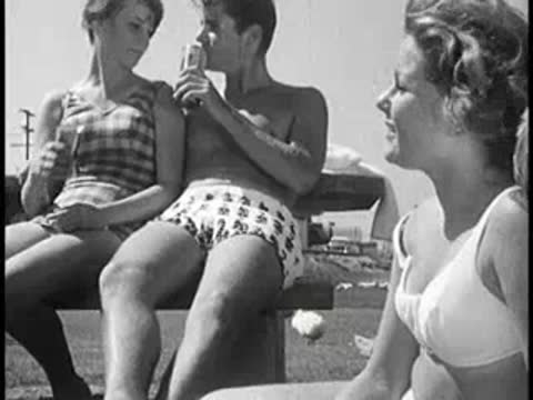 Two young couples sitting outdoors, one man drinking from a can.