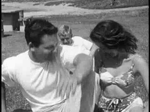 Young couple talking on grass, then getting up quickly.