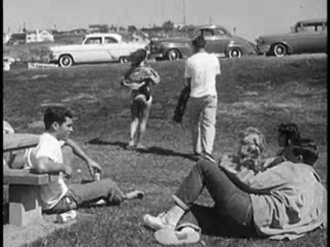 People packing up and walking away from a park picnic area.