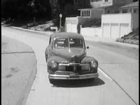 Vintage car approaching and driving forward on a suburban street.