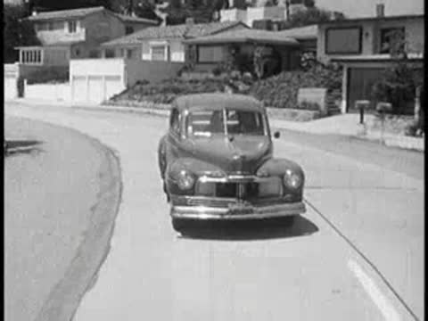 Vintage car driving and turning around a corner on street.