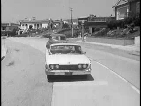 Cars driving along a winding suburban street, view from ahead.