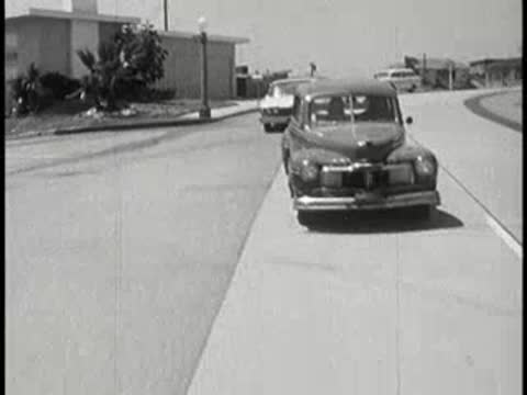 Vintage car approaching on a sunny residential suburban street.