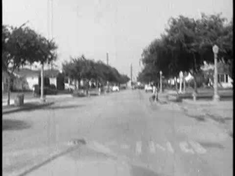 Driver's POV driving down suburban street, child on bicycle appears, vintage car hood, 1960s