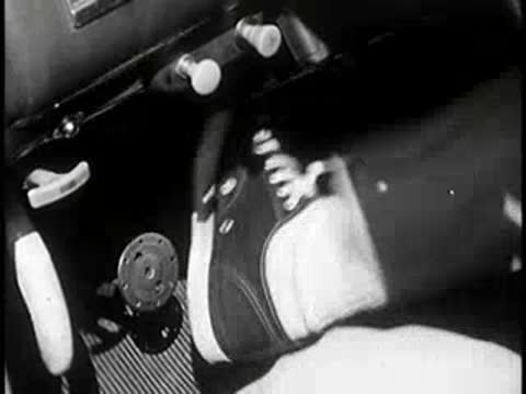 Driver's foot slamming on brake pedal in vintage car interior, 1960s