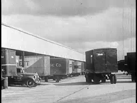 Industrial loading area with parked trucks and large warehouses.