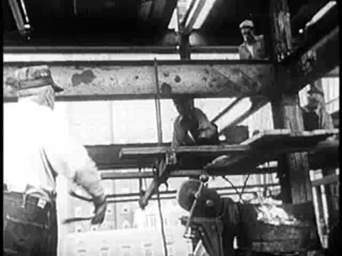 Construction workers welding metal beams inside a building framework.