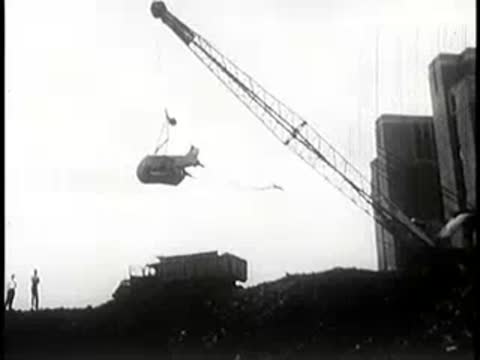 A crane lifting heavy construction material on a hillside site.