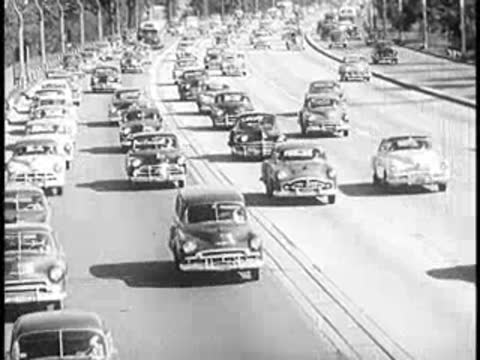 Heavy traffic of vintage cars driving along a multi-lane highway.