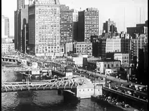Busy city waterfront with bridges and buildings from an elevated view.