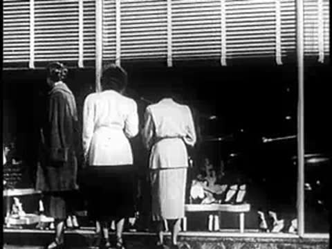 Three people seen from behind standing inside a storefront window.