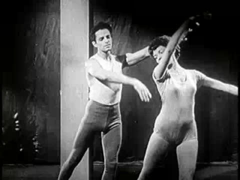 Medium shot of a man and woman dancing modern choreography in a studio.