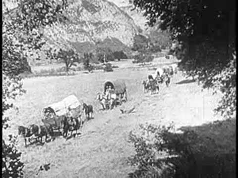 Covered wagons pulled by horses moving across a rural field in early America