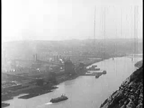 Elevated view of a river with industrial factories and barges along the banks