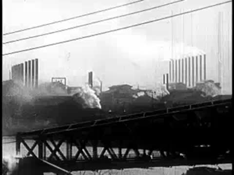 Industrial waterfront with a large bridge structure and factory smokestacks