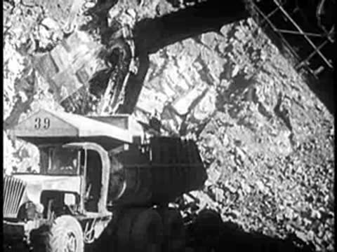 An excavator loads dirt into a dump truck.