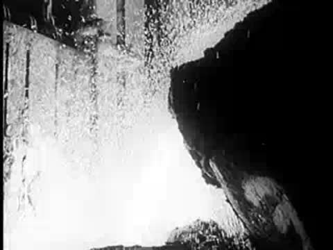 Molten metal pouring from a large industrial container.