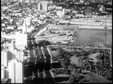High-angle view of a coastal city with parks and buildings.