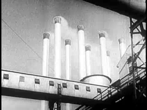 Tall industrial smokestacks emit steam against a bright sky.