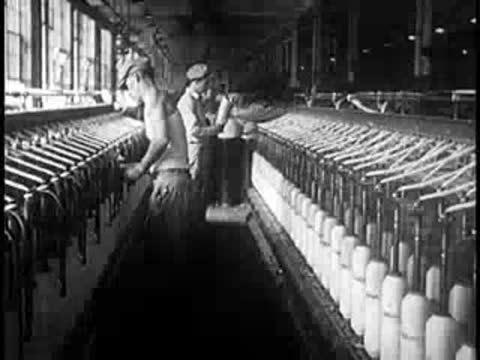 Workers monitor machinery inside a large industrial textile mill.