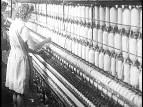 Female textile workers monitor rows of industrial spinning machines.