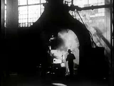 Industrial interior with a worker standing near heavy machinery and steam