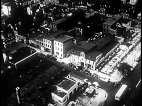 Aerial view of a city neighborhood with buildings, streets, and vehicles