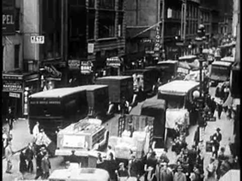Busy city street filled with moving delivery trucks and pedestrians, 1940s urban scene