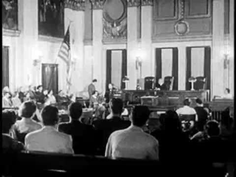 Audience seated in a courtroom facing the judges' bench during a legal proceeding