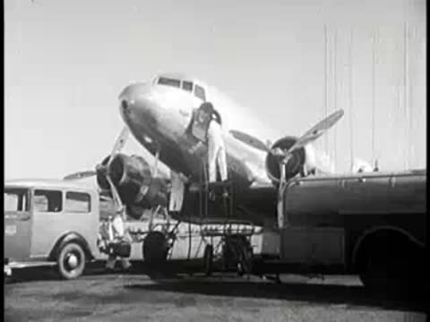 Ground crew member working on the engine of a parked passenger airplane on an airfield