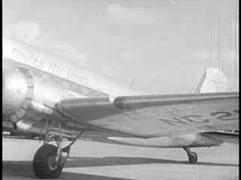A vintage passenger airplane parked on the tarmac, propellers visible.