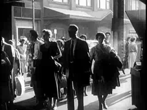 People walking and shopping on a busy city sidewalk outdoors.