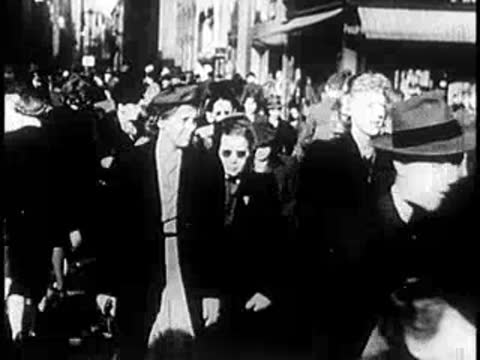 A dense crowd of people walking along a bustling city street.
