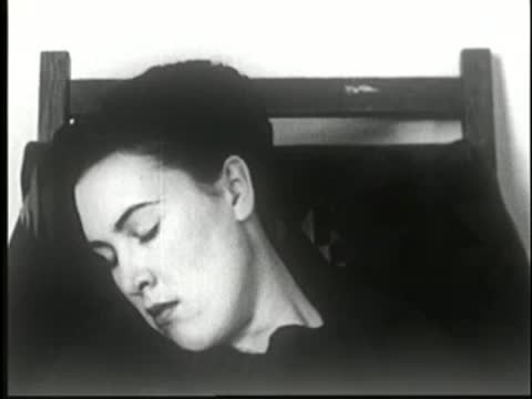 Woman sleeping soundly with her head resting heavily to the side in the chair, static medium shot.