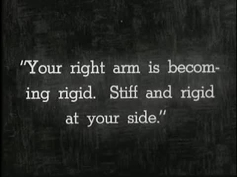 Intertitle stating instructions about the right arm becoming rigid, static black and white.