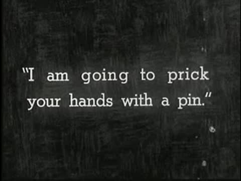 Intertitle on dark background reading: I am going to prick your hands with a pin.