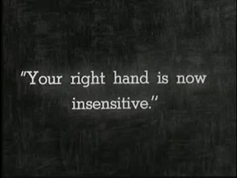 Intertitle on dark background reading: Your right hand is now insensitive.