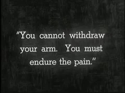 Intertitle on dark background reading: You cannot withdraw your arm. You must endure the pain.