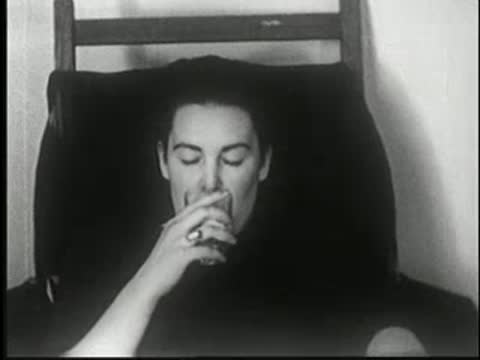 Hypnotized woman drinking from a glass, then showing a grimacing reaction.