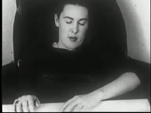 Hypnotized woman resting at table after drinking, eyes closed peacefully.