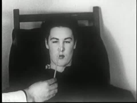 Woman sits in a chair in a dark room, facing forward.