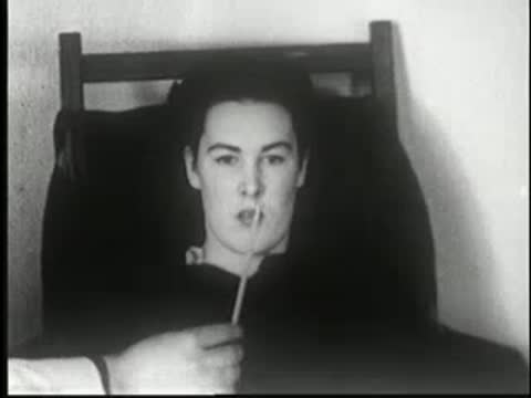 Woman sits in a chair in a dark room, facing forward.