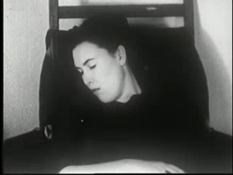 Woman sleeps sitting in a chair, head tilted to the side.