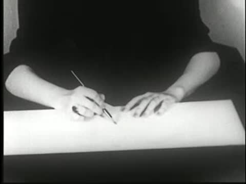 Close-up of hands writing with a pencil on paper.