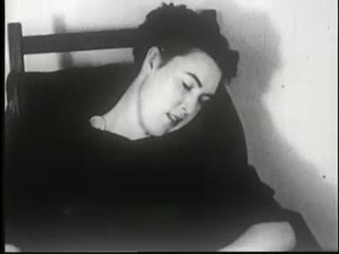 Woman falls asleep sitting in a chair, head resting on her shoulder.
