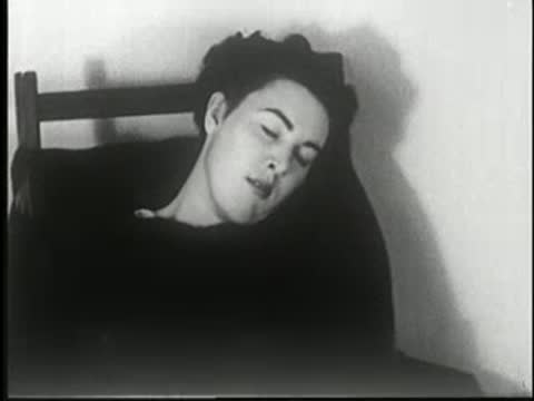 Woman sleeps deeply sitting in a chair, head tilted back.
