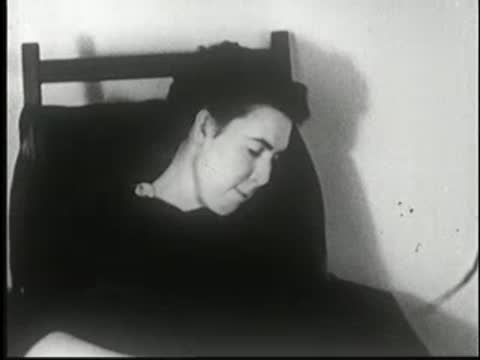 Woman sleeps sitting in a chair, head tilted to the side.