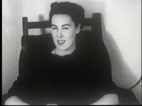 Woman sits at a table, being handed a magazine labeled LIFE.