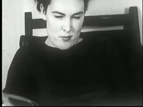 A person sitting and looking down at a magazine, black-and-white.