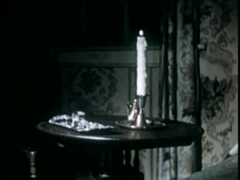 Lit candle on small table next to draped window